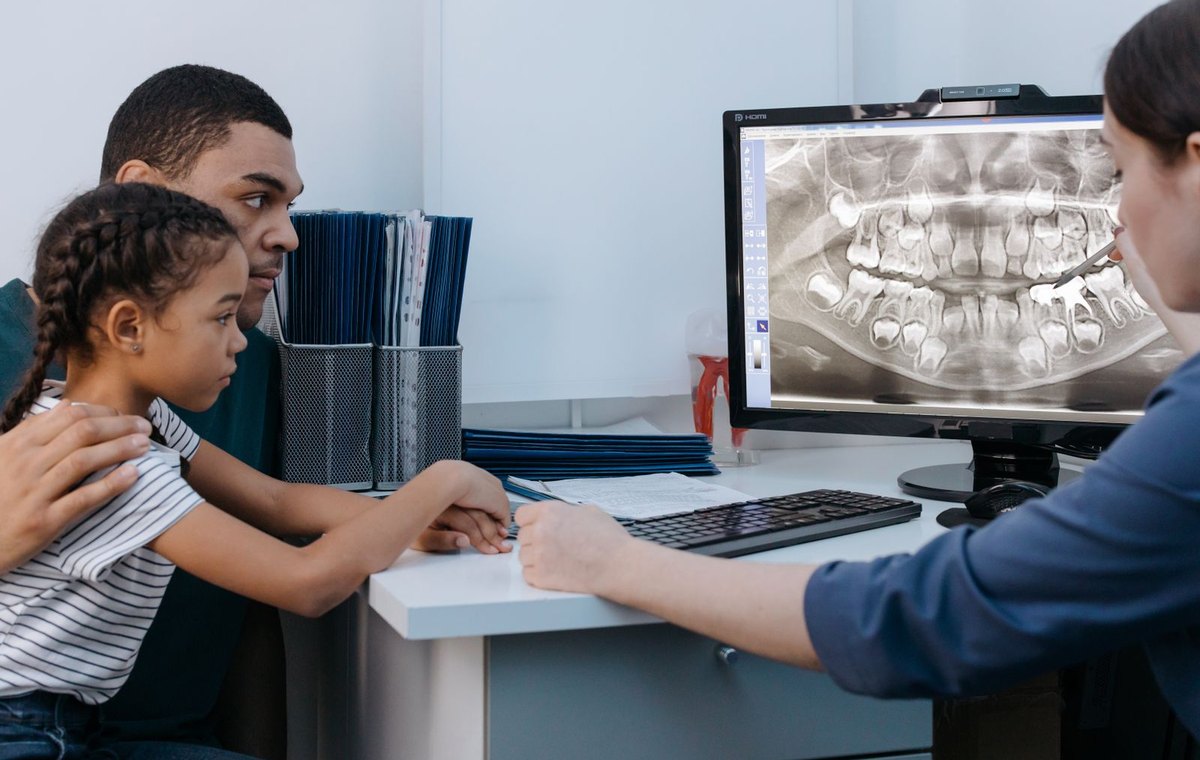 A family looking at a dental x-ray on screen with a clinician